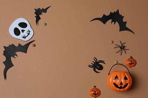 istock Elegant Halloween decor. Top view capturing thematic elements: small orange and golden pumpkins, insects, scary spiders, cobwebs, bats. Empty space for greetings or promotions. 2242819552