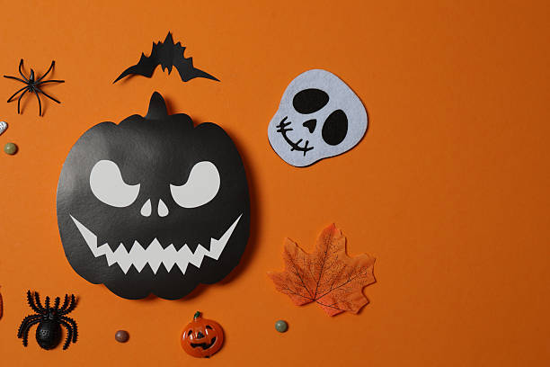 istock Elegant Halloween decor. Top view capturing thematic elements: small orange and golden pumpkins, insects, scary spiders, cobwebs, bats. Empty space for greetings or promotions. 2242819573