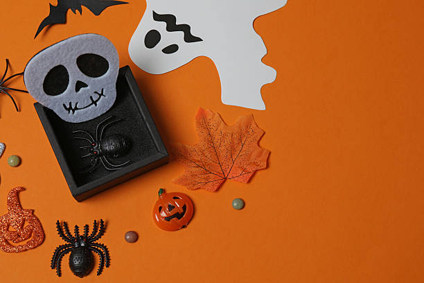 istock Elegant Halloween decor. Top view capturing thematic elements: small orange and golden pumpkins, insects, scary spiders, cobwebs, bats. Empty space for greetings or promotions. 2242819583