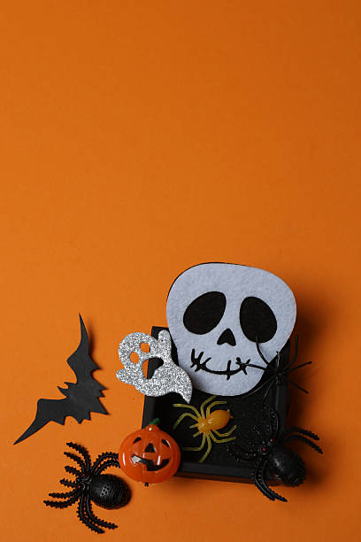 istock Elegant Halloween decor. Top view capturing thematic elements: small orange and golden pumpkins, insects, scary spiders, cobwebs, bats. Empty space for greetings or promotions. 2242820106