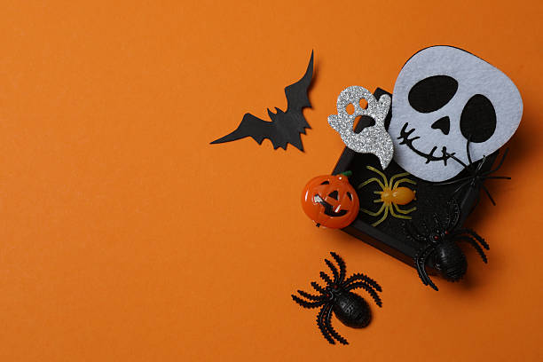 istock Elegant Halloween decor. Top view capturing thematic elements: small orange and golden pumpkins, insects, scary spiders, cobwebs, bats. Empty space for greetings or promotions. 2242820108