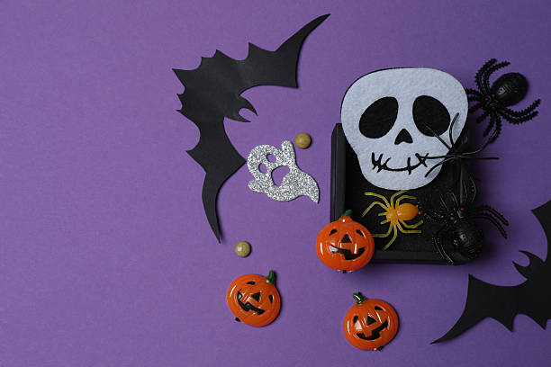 istock Elegant Halloween decor. Top view capturing thematic elements: small orange and golden pumpkins, insects, scary spiders, cobwebs, bats. Empty space for greetings or promotions. 2242820119