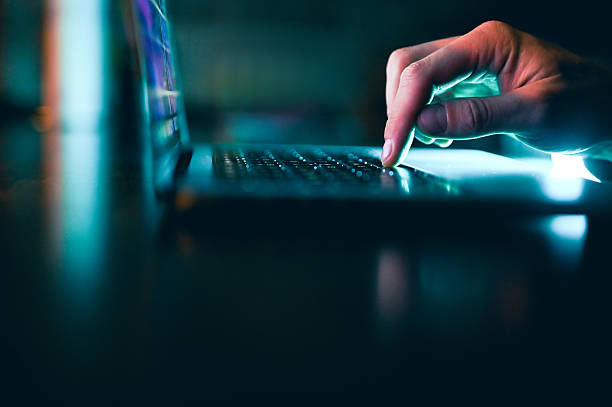 istock Person typing on laptop in dark, glowing light 2242820379