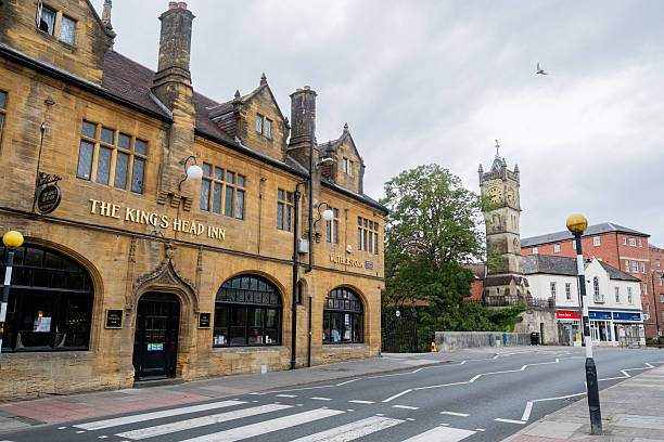 Salisbury UK: 27th July 2025: footbridge Kings Head Inn and famous Salisbury Clock Tower nestled alongside the river