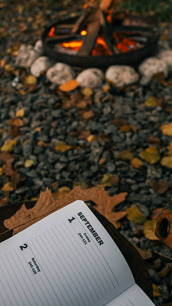 istock Cozy autumn scene with a campfire, calendar, and fall foliage in September 2242825552