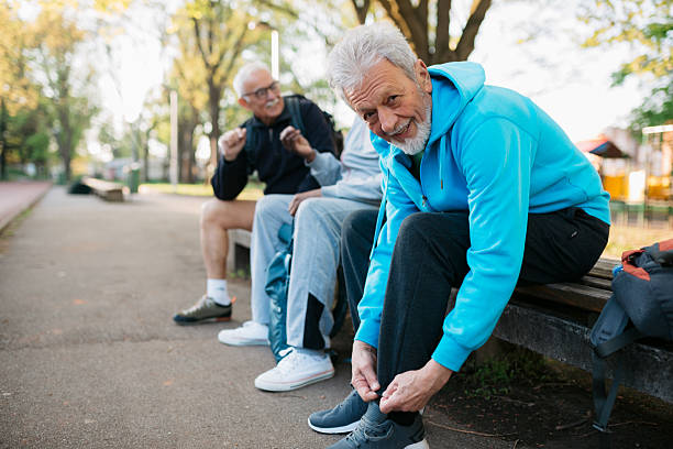 istock Senior man tying shoelaces before park exercise with friends 2242836793