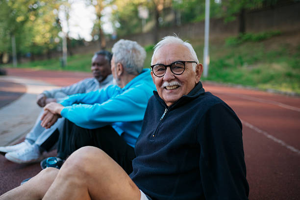 Three senior men sitting on a track, smiling at the camera