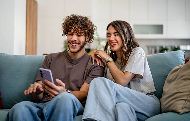 istock Young couple laughing using mobile phone at home 2242837099