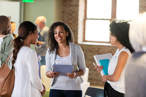 istock Diverse group of women engage in conversation at an indoor networking event, holding tablets and notebooks. 2242840159