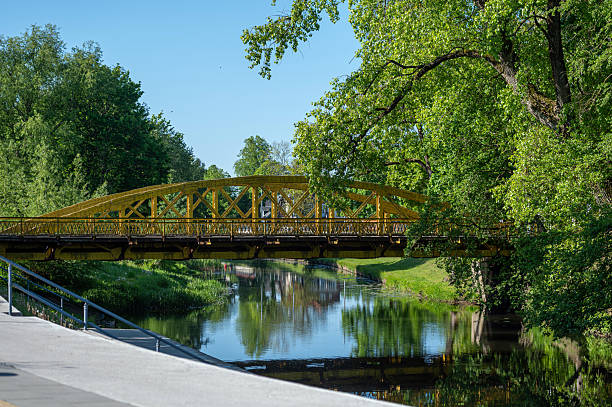 istock A vibrant, yellow bridge crossing a serene river with trees reflecting in the water. 2242848159