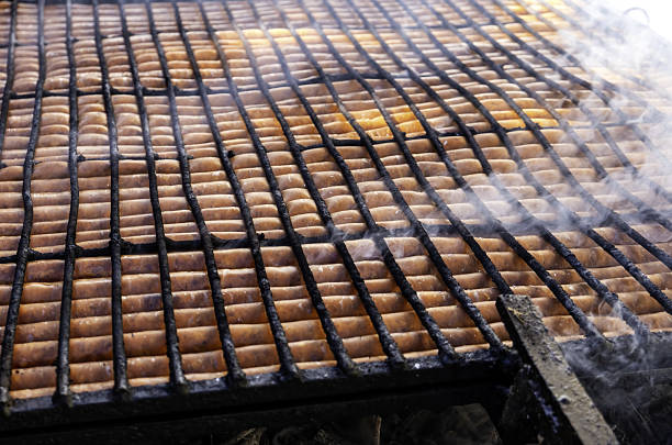 Chicken sausage is fried on the grill. Sausages in a metal grate are cooked over coals