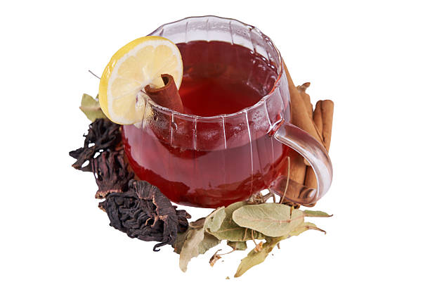 Star anise, cinnamon sticks, tea, and a sliced orange placed in a clear empty glass on a wooden table, ingredients for a warming winter tea