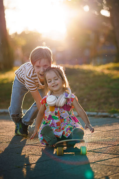 istock Children playing with a skateboard together in a park at sunset. 2242859562