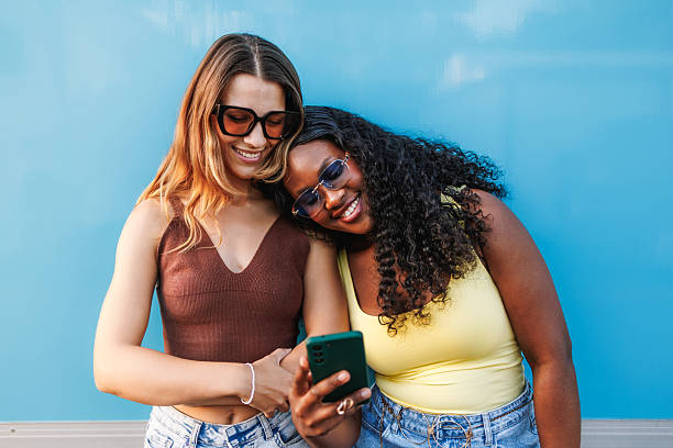 istock Diverse women smiling, looking at a smartphone screen, and sharing online content 2242867311