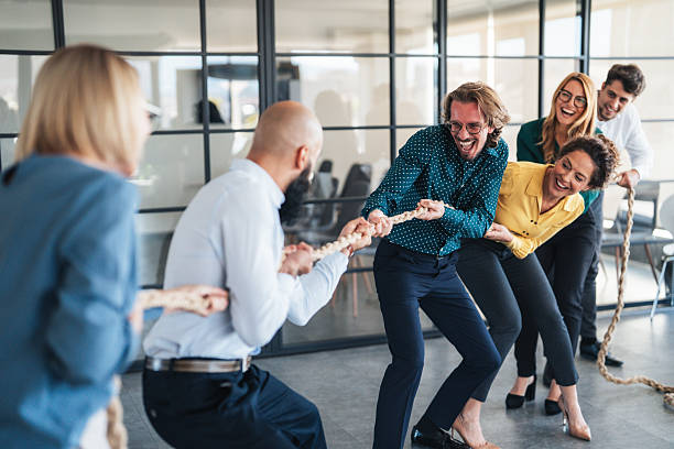 istock Playful colleagues having fun while playing tug-of-war in the office 2242867959