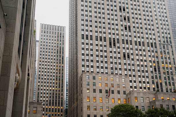 Rockefeller center’s classic skyscraper architecture with many windows and an american flag flying in new york city