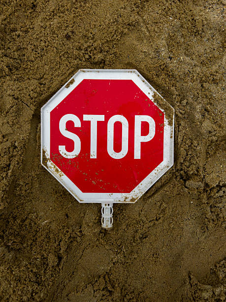 Red stop sign lying on sand — warning symbol representing caution, restriction, and safety concept. Traffic sign on ground background for risk, danger, or alert message themes