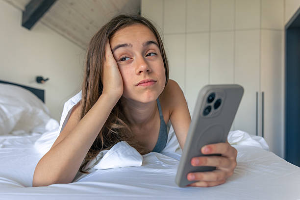 istock Girl bored with smartphone in white bed at morning. Sleepy doomscrolling. 2242876113