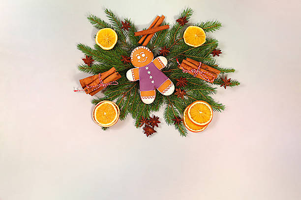 Beautiful holiday decoration made of live fir branches, cinnamon, dried oranges, star anise and gingerbread, isolated on bright background, Christmas template for design, Christmas composition and New Year 2026 concept, banner for winter screen,