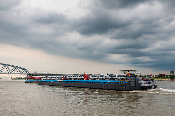 A large tanker ship sailing in Germany on the Rhine river visible storage silos, fuel depot of petroleum and gasoline on the banks river, loading port, heavy sea traffic.
