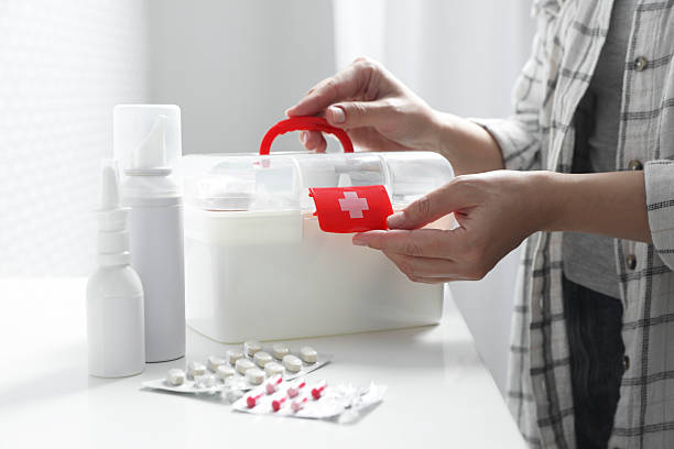 istock Woman opening first aid kit at white table indoors, closeup 2242890859