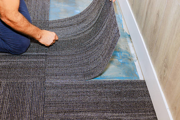 istock Worker installing gray carpet tiles in modern office space, flooring upgrade process 2242897581