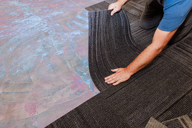istock Worker installing carpet tiles on floor in modern indoor space 2242897584