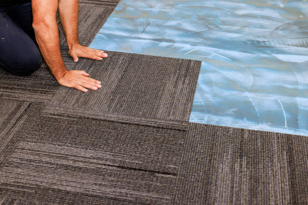 istock Worker installing gray carpet tiles in an office space during work 2242897589