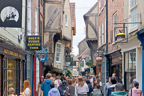 London, England - July 22, 2025: View along The Shambles in York, a narrow medieval street with timber-framed buildings housing shops and cafés. The scene shows the busy pedestrian area that retains its characteristic overhanging upper stories and historic layout.