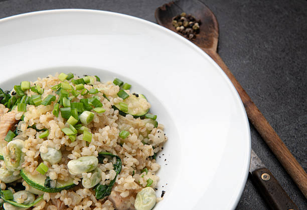 Freshly cooked risotto with broccoli, rice, and herbs served in a white bowl on rustic table.