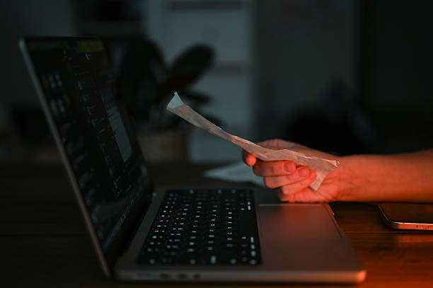 istock Person holding receipt, managing finances on laptop at night 2242904237