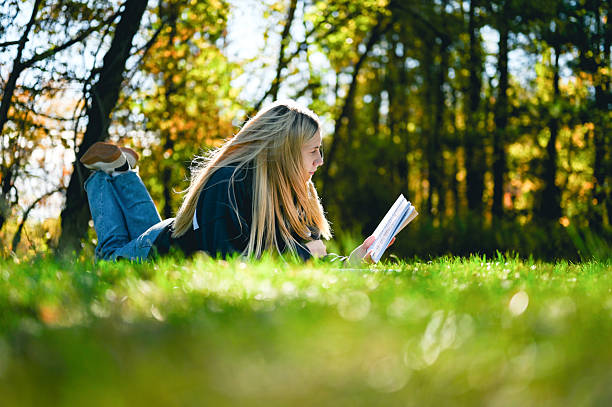 Young woman turning aside out of curiosity or after an interruption looking behind her with a quizzical expression as she lies relaxing on a wooden garden bench