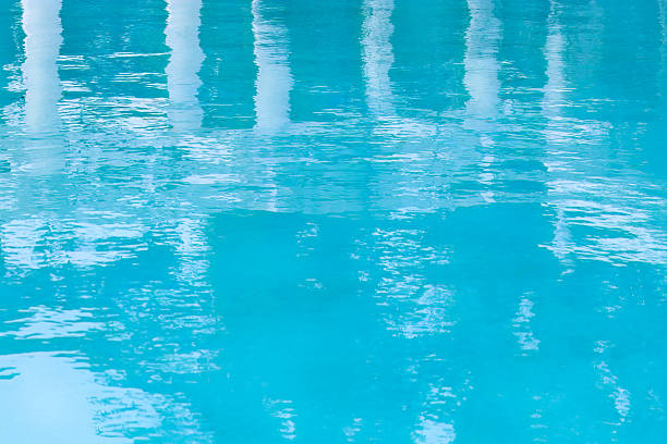 Turquoise outdoor pool with  reflection of snow-white columns. Abstract water surface with ripples. Blue texture background. Summer vacation concept.