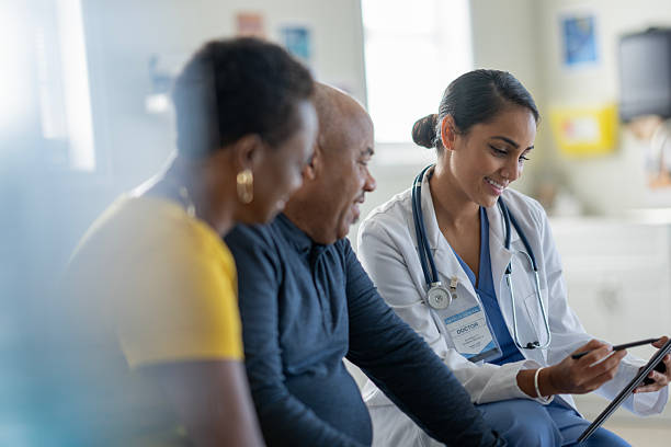 istock Multicultural Doctor and Two Patients Discuss Health Using Tablet in Bright Clinic Setting 2242910632