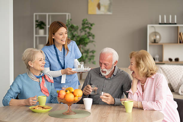 istock Cheerful Caregiver Sharing Refreshments with Seniors Together 2242911312