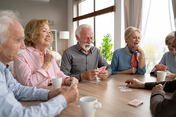 istock Group of Seniors Laughing While Playing Cards in Cozy Space 2242911351