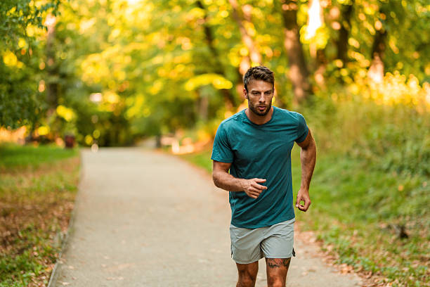 istock Athletic man jogging through the park. 2242912797