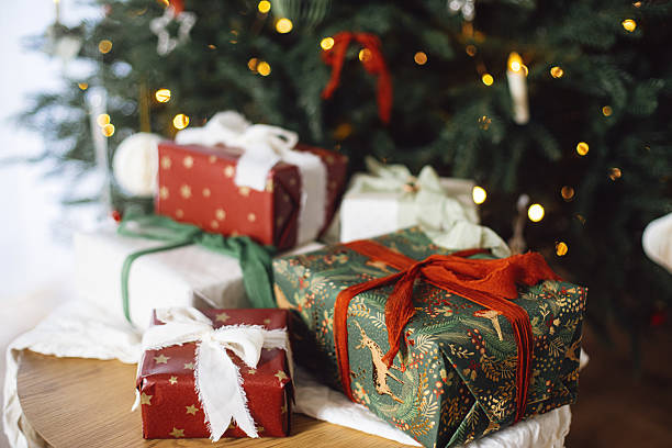 istock Stylish Christmas gift boxes on table at decorated xmas tree with lights. Merry Christmas 2242913035