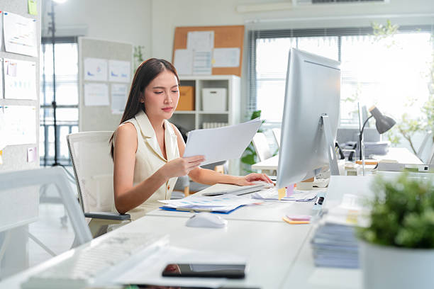 istock Young businesswoman is actively using a computer at her desk in the office. She's focused on working on the computer in the office, showcasing her professional dedication 2242914023