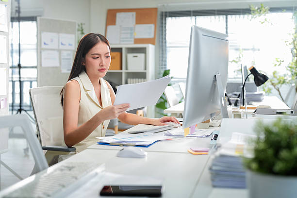 istock Young businesswoman is actively using a computer at her desk in the office. She's focused on working on the computer in the office, showcasing her professional dedication 2242914027