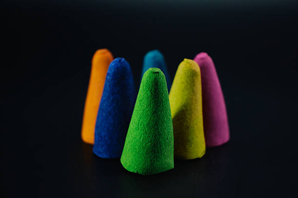 Macro still life of colorful incense cones arranged on a black surface. Represents meditation, aroma therapy, spirituality, and relaxation.