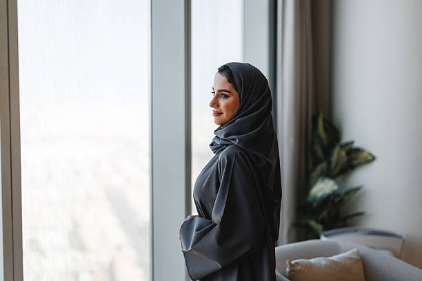 istock Elegant Arabic Woman Standing Thoughtfully by Window in Luxury Apartment Setting 2242939817