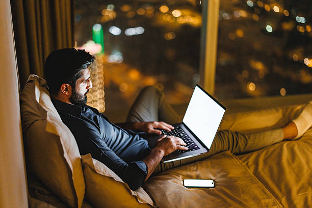 istock Focused Arabic Businessman Using Laptop While Relaxing in a Hotel Room at Night 2242939918