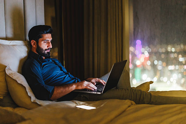 istock Young Middle Eastern Businessman Focused on Laptop Work in Hotel Room at Night 2242939965