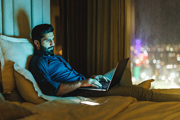 istock Middle Eastern Businessman Reviewing Documents on Laptop in Dimly Lit Hotel Room 2242939985