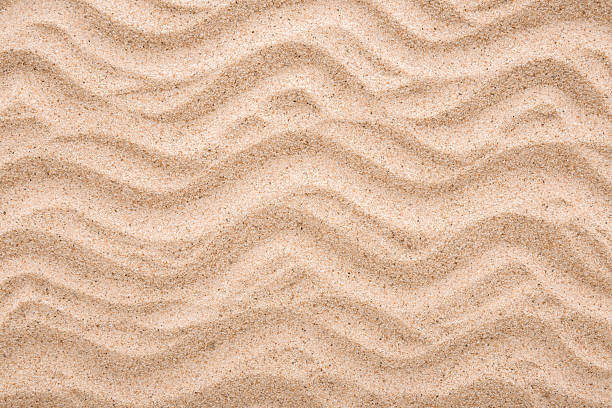 istock Dry light brown wavy sea sand background. Closeup. Top down view. 2242940092
