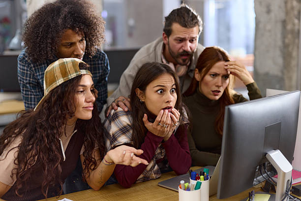 Team of shocked programmers reading problematic codes on desktop PC in the office.