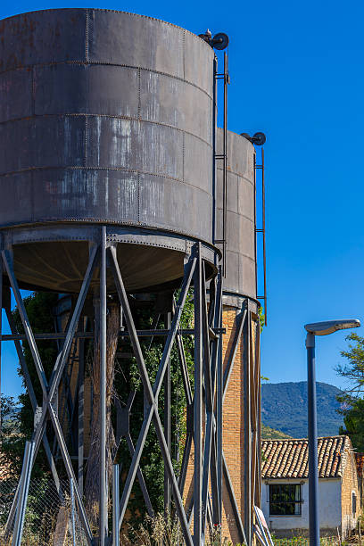 istock Two large metal tanks. A green vine grows on a nearby brick building. 2242943949