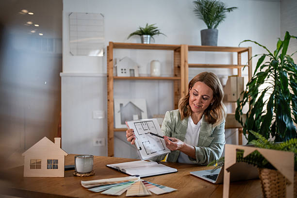 istock Female architect showing house plan for new home design 2242944073