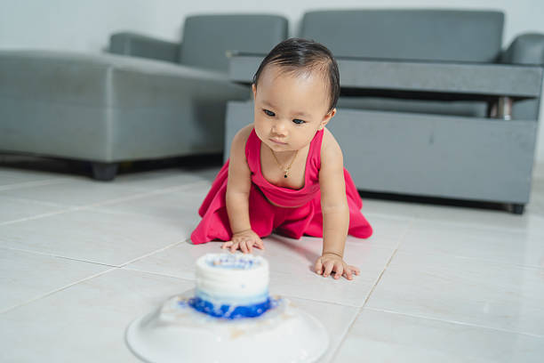 Baby girl playing curiously with small cake, concept of curiosity and early learning.